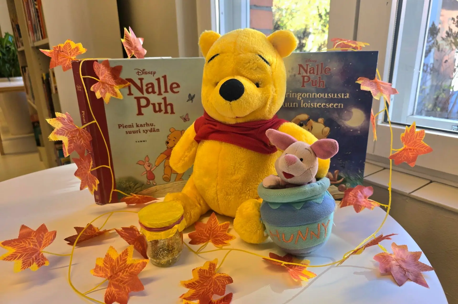 Nalle Puh-pehmohahmo ja kirjoja aseteltuna pöydälle