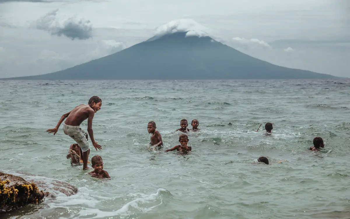 Enfants déplacés jouant en face de l’île volcanique de Manam qu’ils ont dû quitter. © IOM 2016 / Muse Mohammed