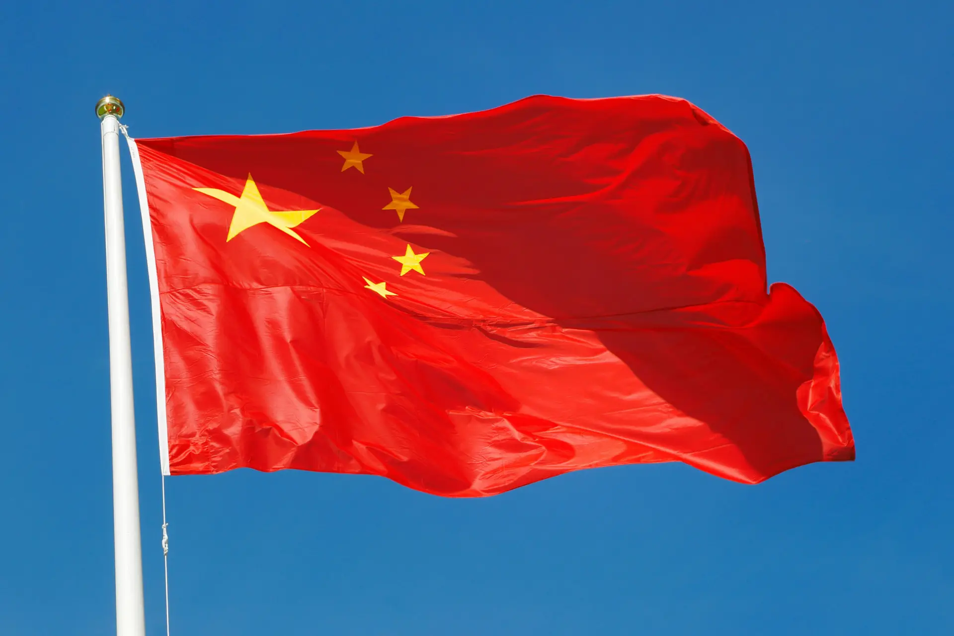 Kiinan lippu liehuu valkoisessa lipputangossa