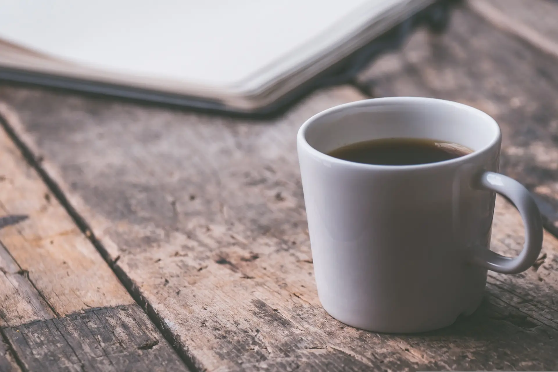 En kopp med svart kaffe och en anteckningsbok.