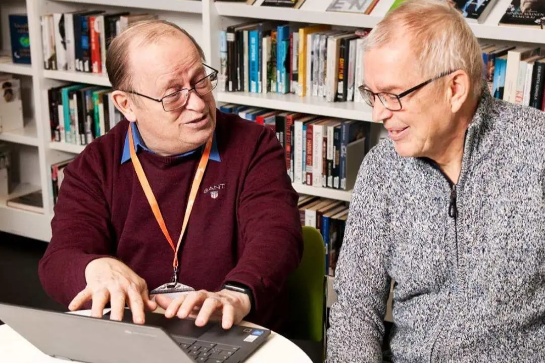 Kaksi herraa läppärin ääressä kirjastossa